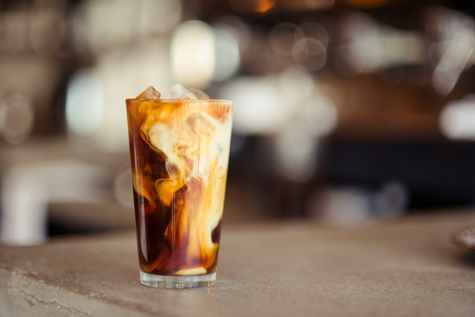 A tall glass of cold brew coffee over ice on a wooden table