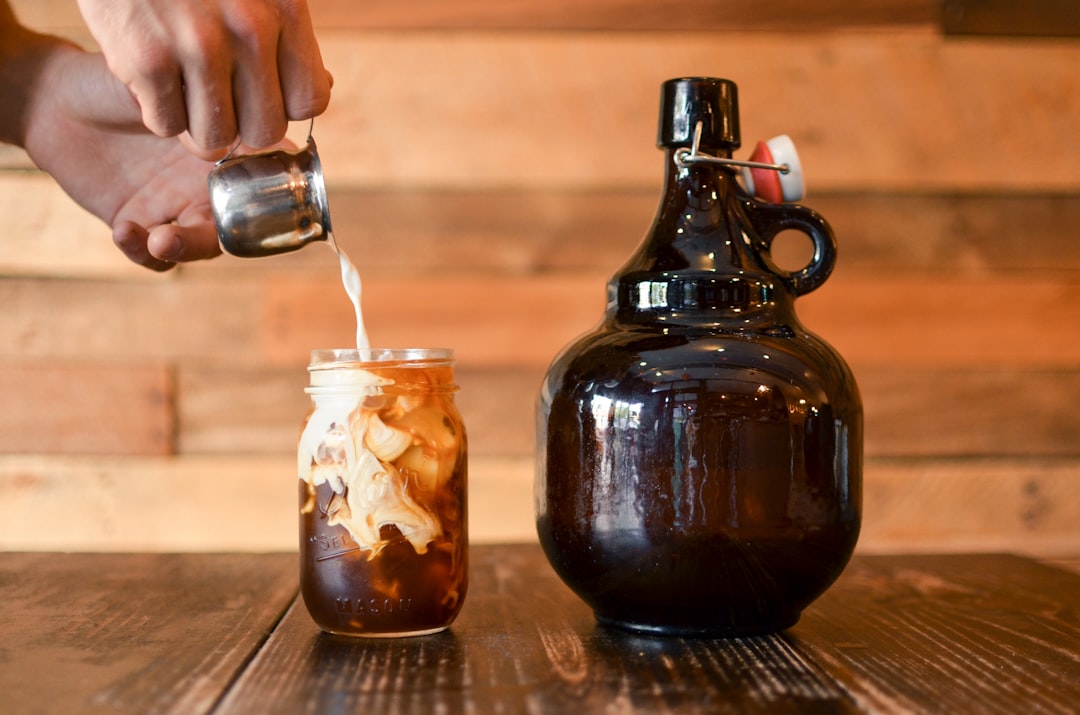 A glass jar of dark cold brew coffee concentrate next to ice and a pour over pitcher