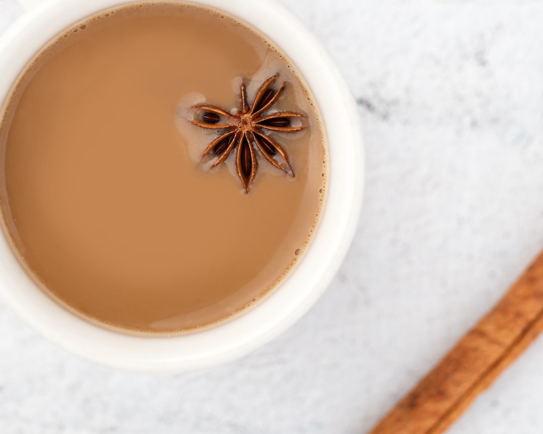 A mug of steeping masala chai tea with visible spices and steam