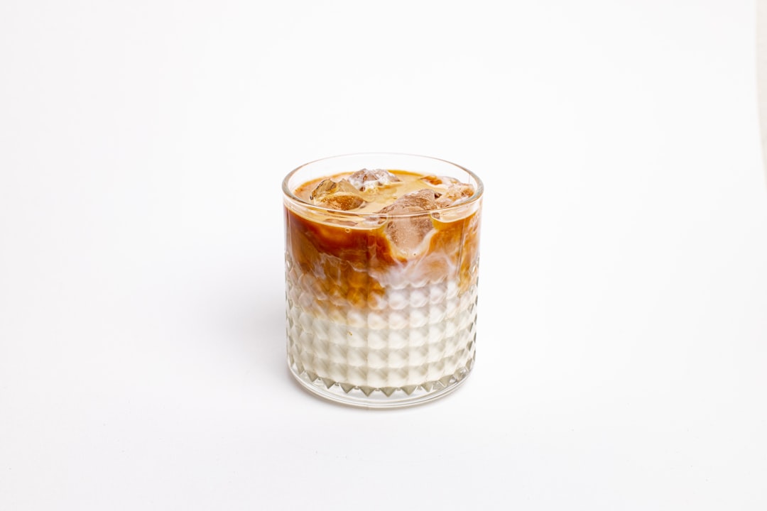 Iced chai latte with milk swirl in a glass over ice, surrounded by loose spices